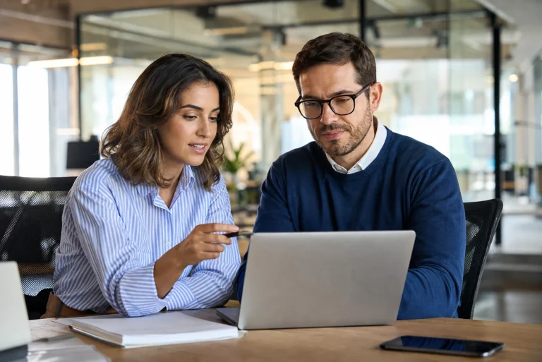 Consultant et responsable d'entreprise qui analysent ensemble un projet ERP sur un ordinateur portable