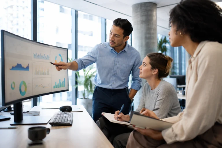 Équipe de professionnels analysant des indicateurs KPI sur un tableau de bord Business Intelligence dans un bureau moderne
